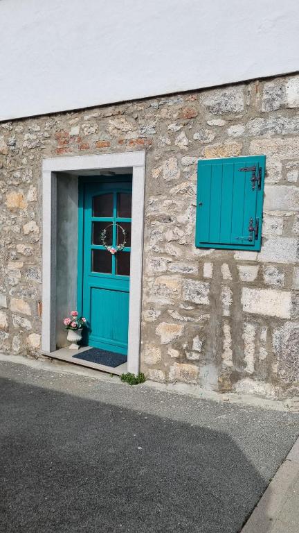 a building with a blue door and a window at Comfortable Apartment & Studio in Village Centre in Komen