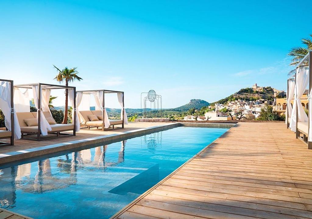 a pool at a resort with chairs and palm trees at Hotel Creu de Tau Art&Spa-Adults only in Capdepera