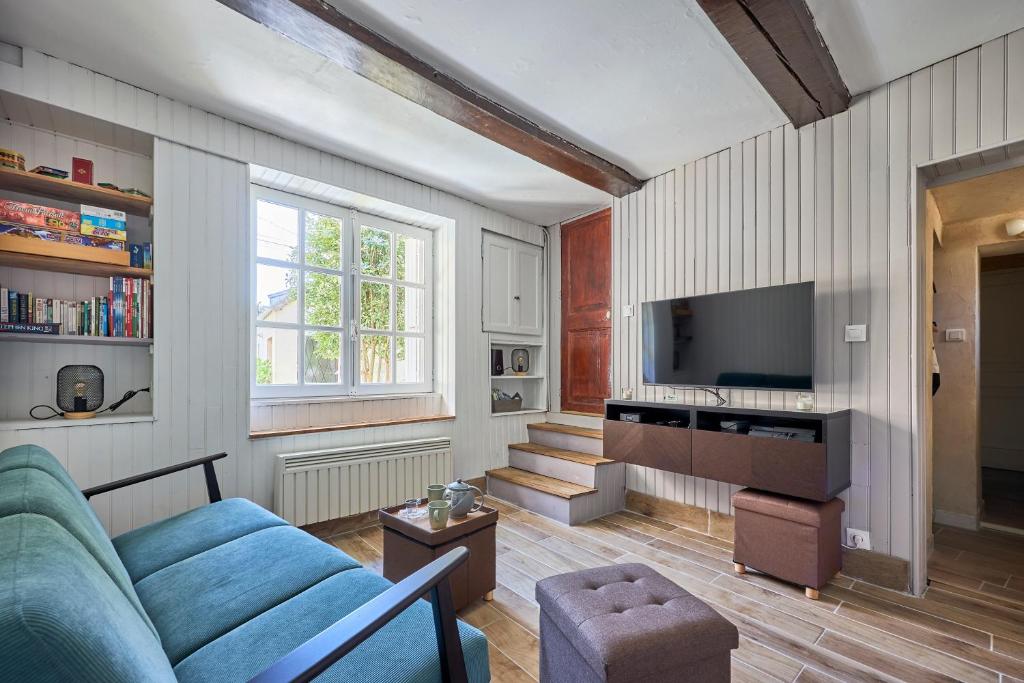 a living room with a blue couch and a tv at Augustine Beach - Maison à 700 m de la plage in Courseulles-sur-Mer