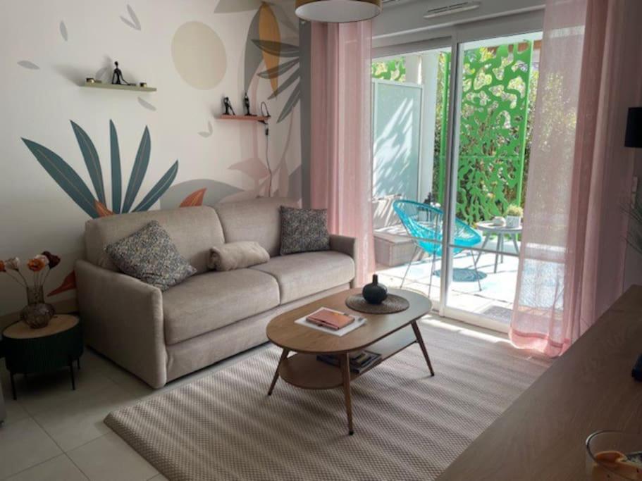 un salon avec un canapé et une table dans l'établissement T2 avec jardinet parking la genette, à La Rochelle