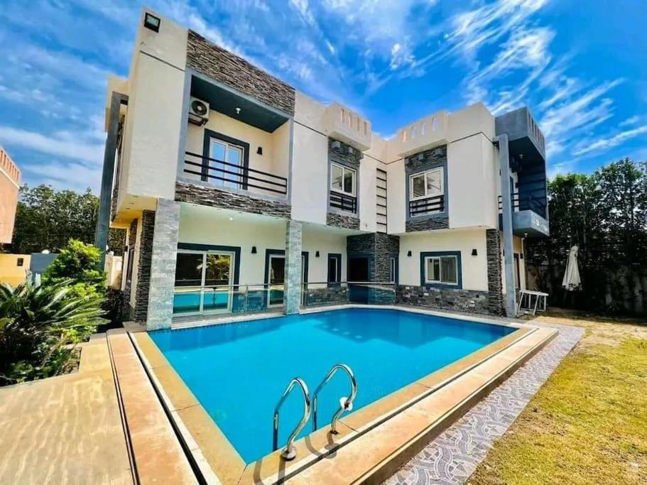 uma casa grande com uma piscina em frente em فيلا مفروشة بالكامل em Naj‘ al Aḩwāl