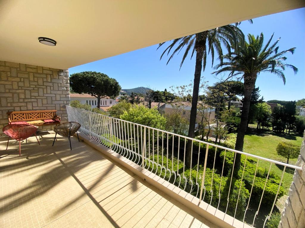 d'un balcon avec un banc et un palmier. dans l'établissement T5 rénové à 4 min de la plage, à Saint-Cyr-sur-Mer