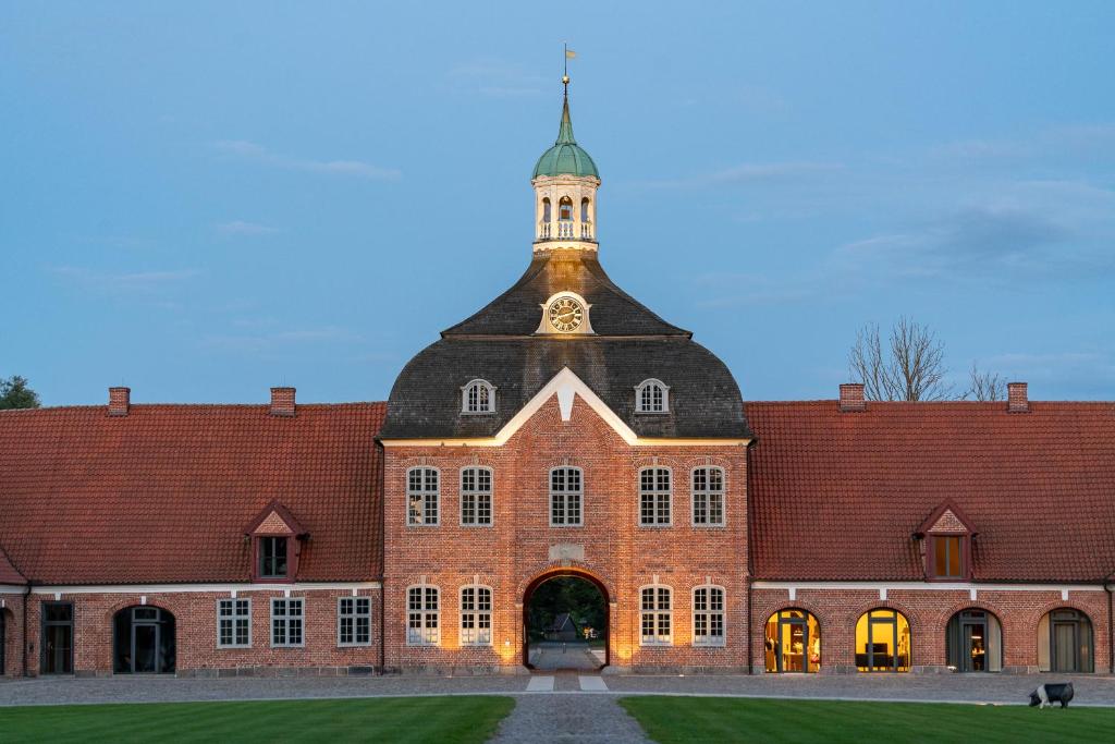 a large brick building with a clock tower on top at Kultur Gut Hasselburg in Altenkrempe