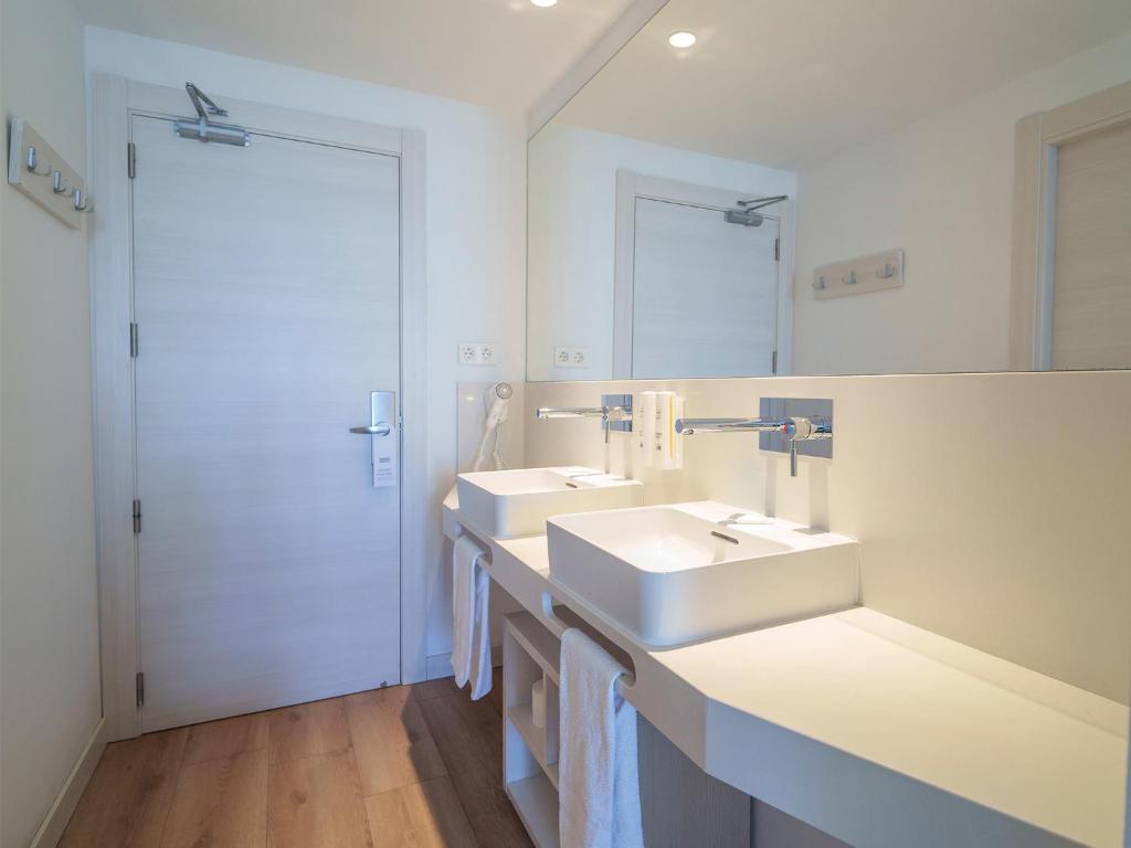 a white bathroom with two sinks and a mirror at Spirit Hotel Benalmadena Beach in Benalmádena