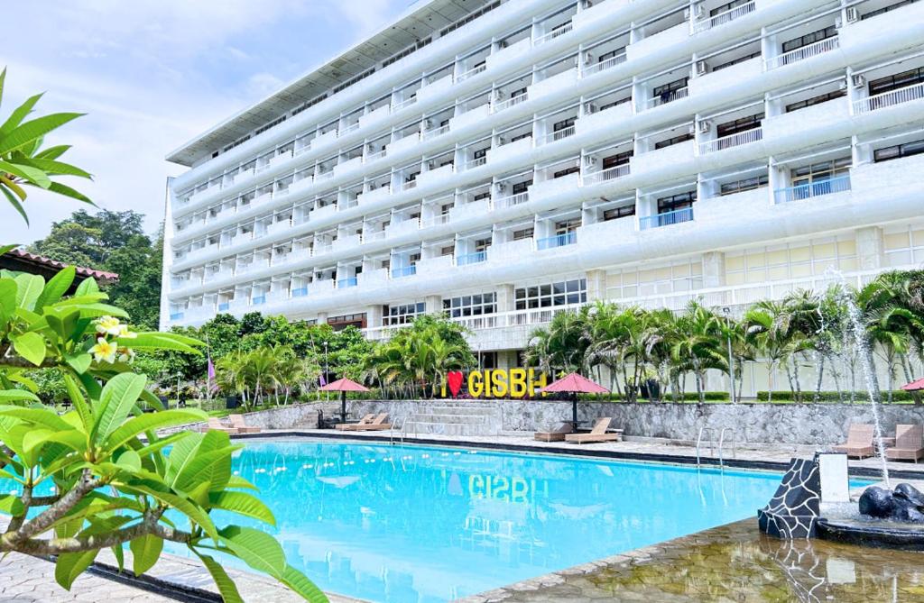 un hôtel avec une piscine en face d'un bâtiment dans l'établissement Grand Inna Samudra Beach, à Cimaja