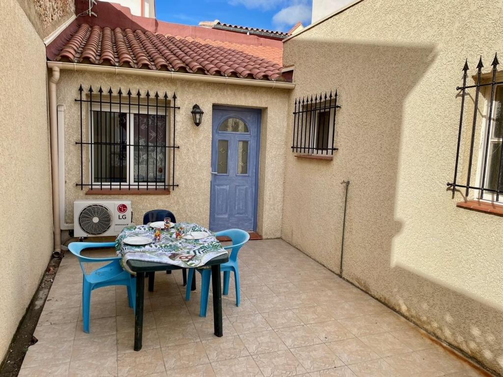 einen Tisch und Stühle auf einer Terrasse mit blauer Tür in der Unterkunft Maison de la Plage in Le Barcarès