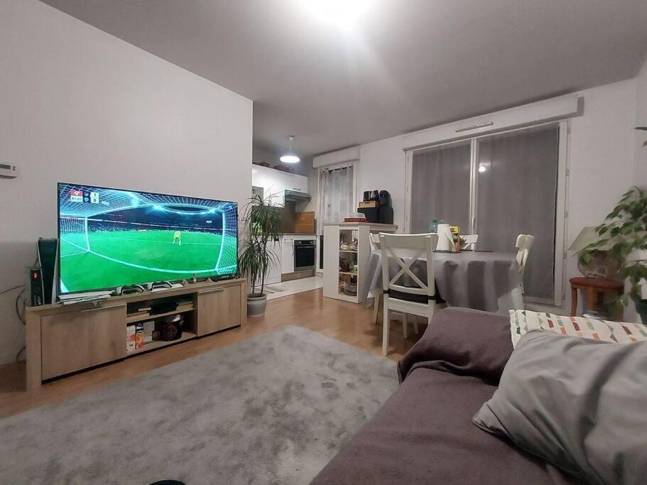 un salon avec une télévision à écran plat et un canapé dans l'établissement Appartement JO Stade de France, à Aubervilliers