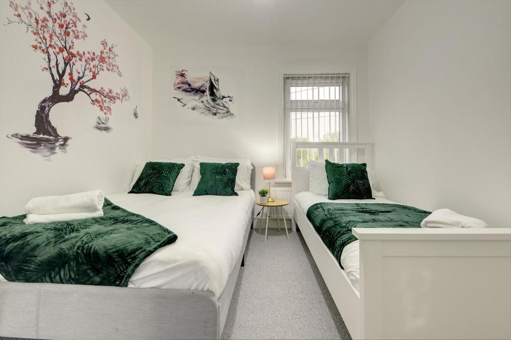 2 łóżka w białym pokoju z zieloną pościelą w obiekcie Stunning and Lovely 3 Bed House - Catch 22 w Coventry