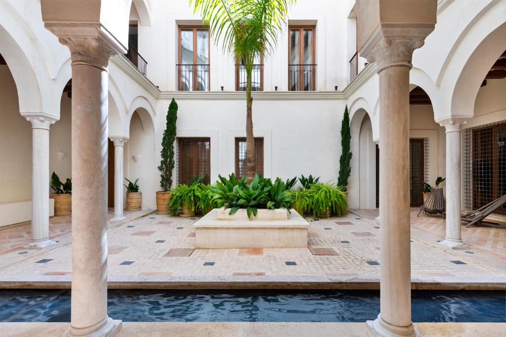 einen Innenhof mit einer Palme und einem Brunnen in der Unterkunft Casa del Rey Sabio in Sevilla