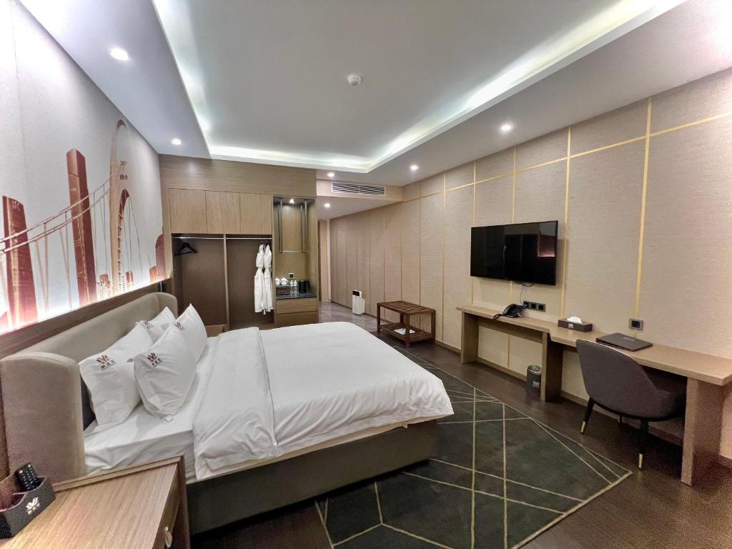 a hotel room with a bed and a desk and a tv at Wah Fu Hotel in Ho Chi Minh City