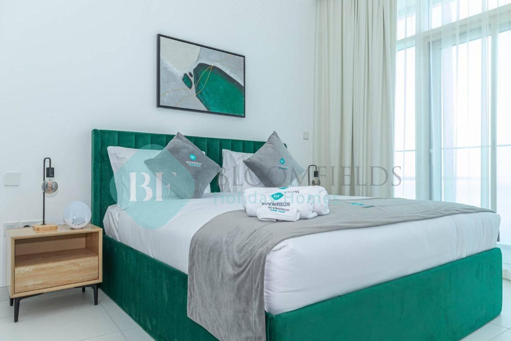 Schlafzimmer mit einem großen Bett mit einem grünen Kopfteil in der Unterkunft Modern 1 Bedroom In Thalassa in Abu Dhabi