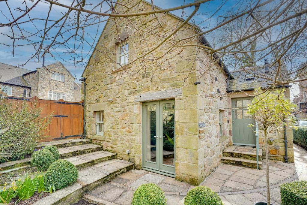 a stone house with a green door and stairs at Garden Stable at Hallsteads: Luxury Stone Cottage, with Parking in Alnmouth