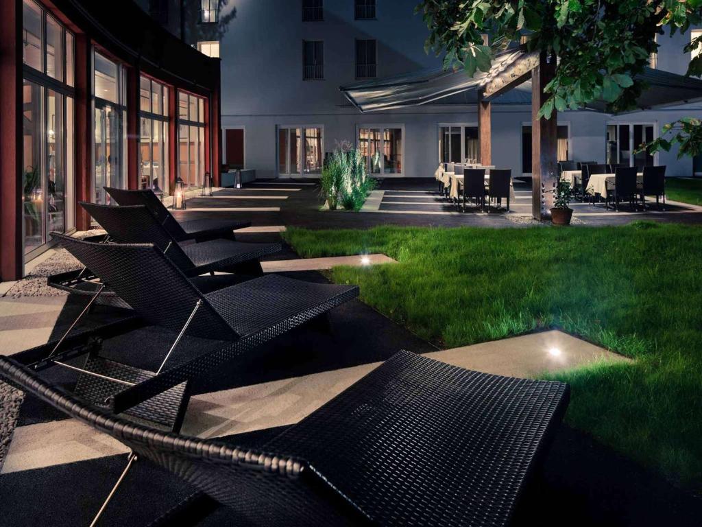 a group of chairs sitting on the grass in a courtyard at Mercure Salzburg City in Salzburg