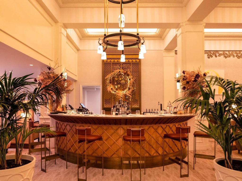 a large lobby with a bar with chairs and plants at Sofitel Le Scribe Paris Opera in Paris
