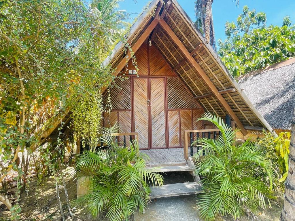 een klein huis met een houten veranda en een trap. bij Binucot Lodge in Romblon