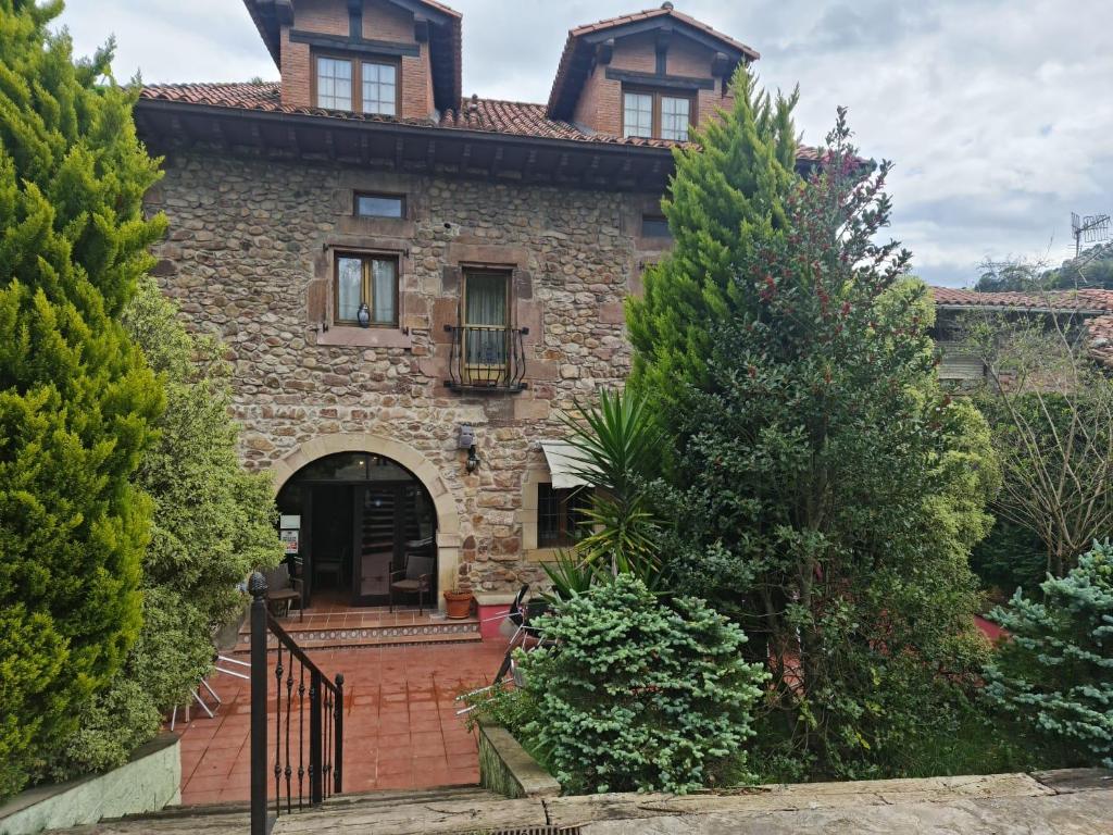 uma antiga casa de pedra com um portão e árvores em POSADA LAS MOZAS DEL AGUA DE GABY Y TINO em Ríocorvo