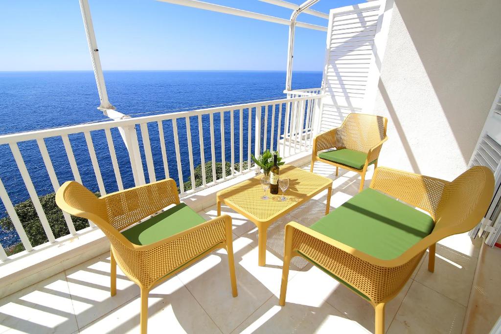 a balcony with chairs and tables and the ocean at Kate's Place in Dubrovnik