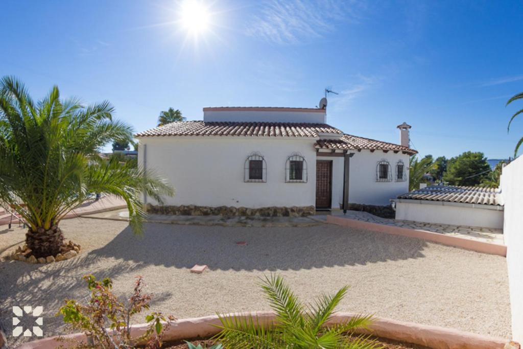 a white house with a palm tree in front of it at Villa Nani by Abahana Villas in Calpe
