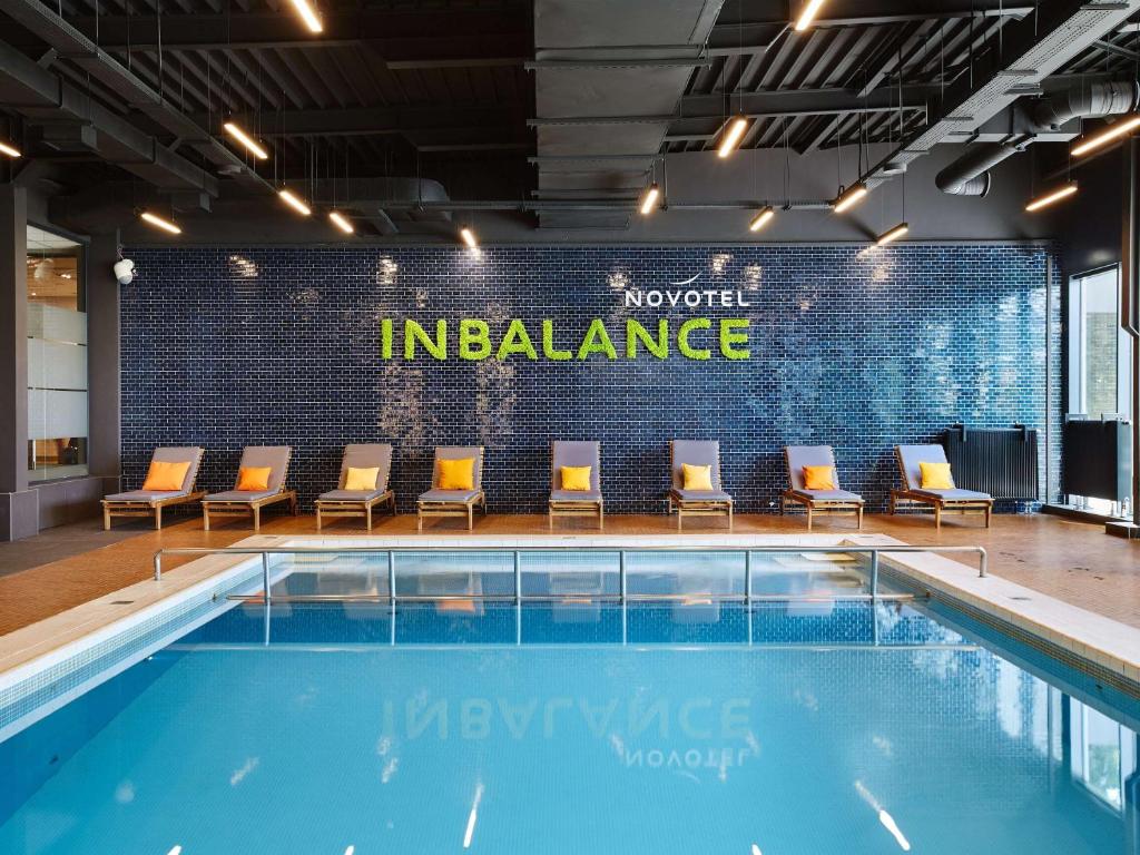 a pool with chairs and a sign that reads invest insurance at Novotel Kraków City West in Krakow