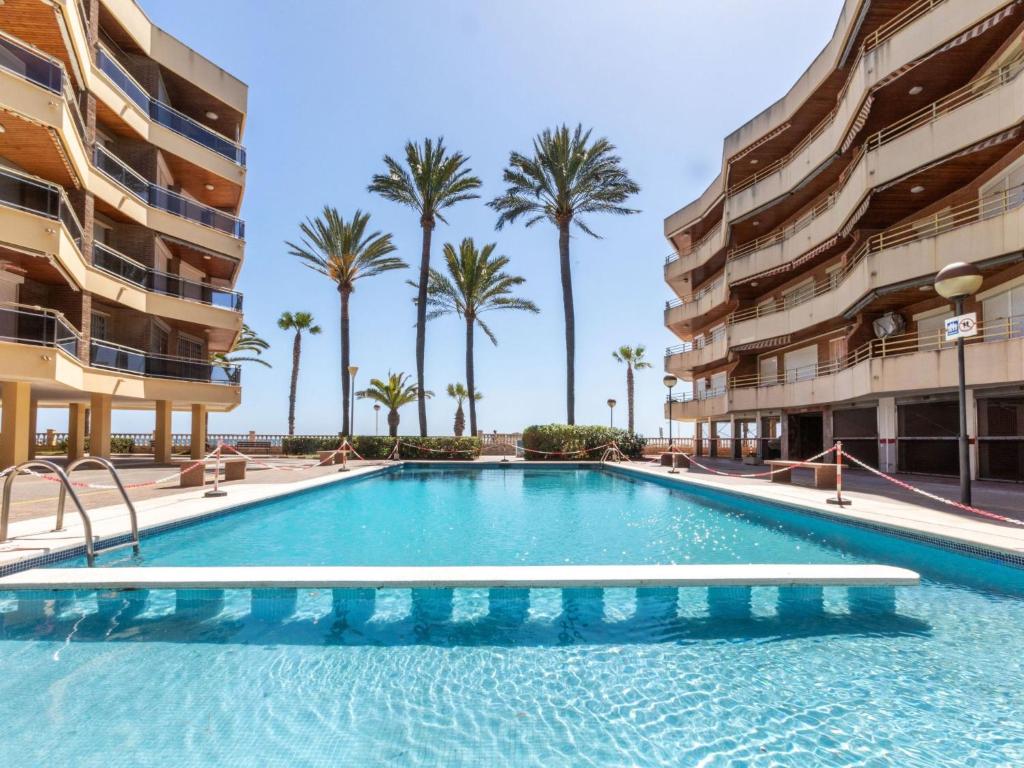 - une piscine au milieu d'un immeuble avec des palmiers dans l'établissement Apartment Marina by Interhome, à Cambrils