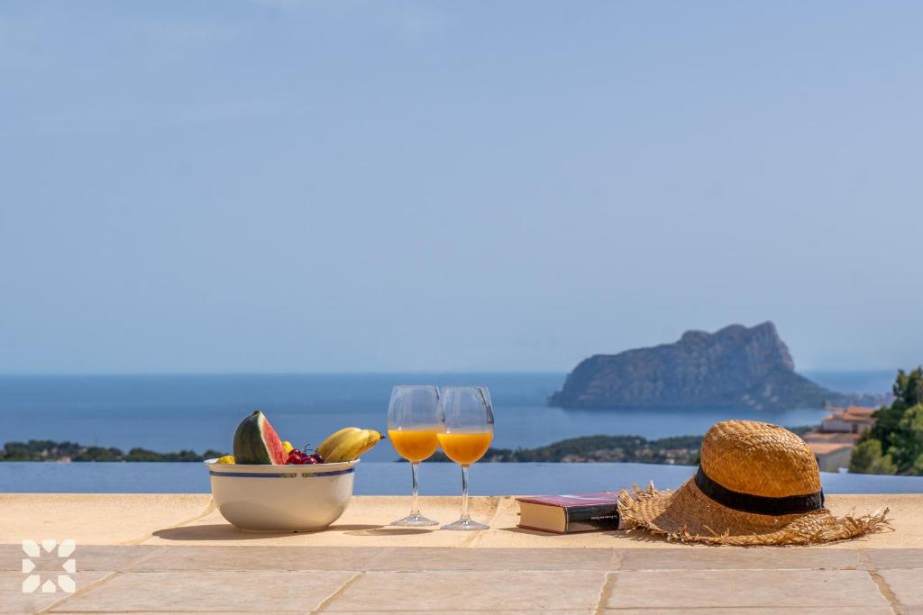 - une table avec deux verres de vin et un bol de fruits dans l'établissement Villa Treveris by Abahana Villas, à Teulada