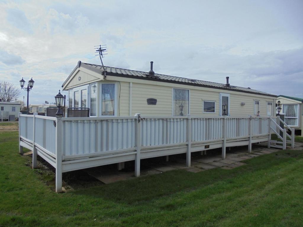 una casa blanca con una valla en el césped en Sapphire 8 Berth panel heated Towervans en Sutton on Sea