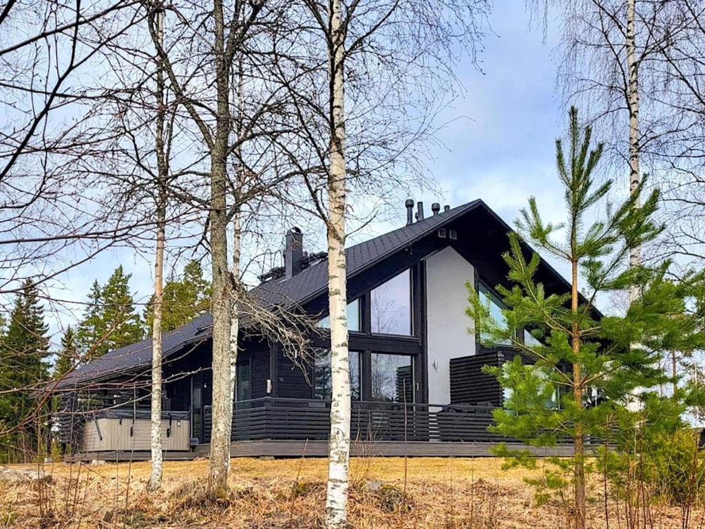ein Schwarz-Weiß-Haus mit Bäumen davor in der Unterkunft Holiday Home Golfarinkunnas 7b by Interhome in Jämsä