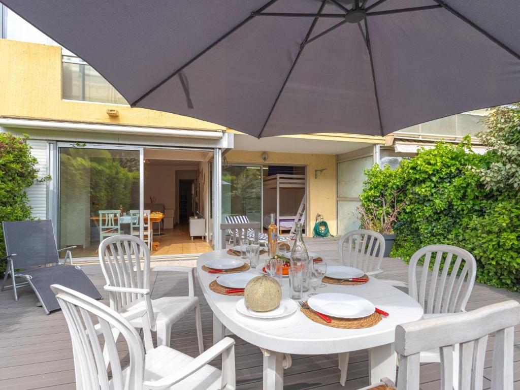 une table blanche avec des chaises blanches et un parasol dans l'établissement Apartment Helios by Interhome, à Six-Fours-les-Plages