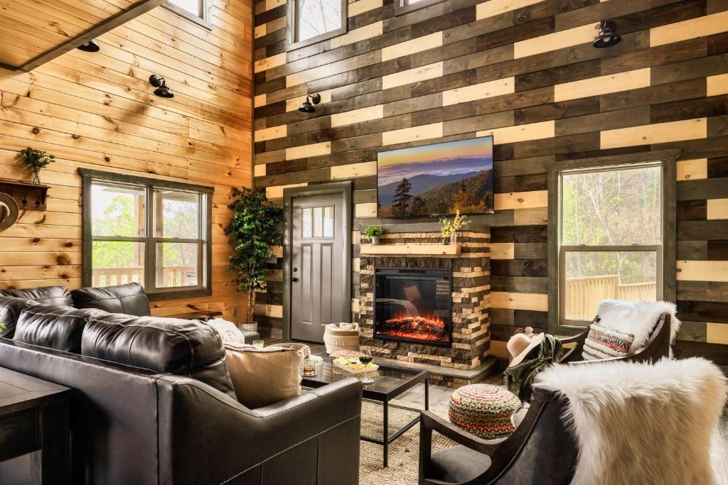 a living room with leather furniture and a fireplace at Mountainscape - Brand New Cabin w Views - HotTub - FireTable - PS5 - PoolTable - 3 Pools in Gatlinburg