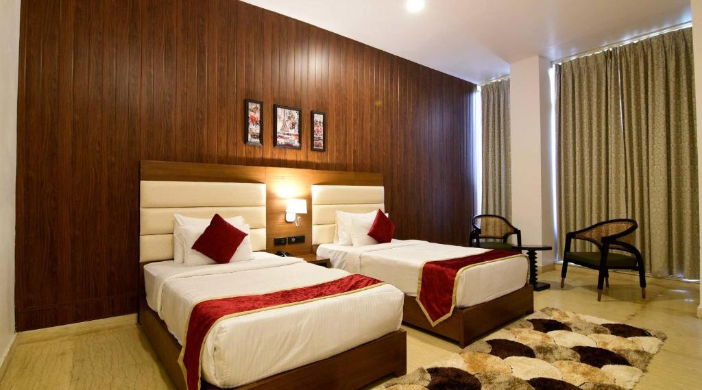 Habitación de hotel con 2 camas y escritorio en Hotel Creastview Inn At International Airport, en Nueva Delhi