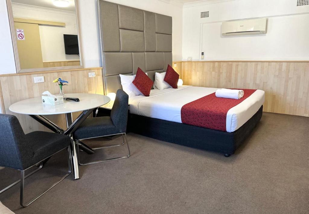 1 dormitorio con 1 cama y 1 mesa con sillas en Countryman Motor Inn Cowra, en Cowra