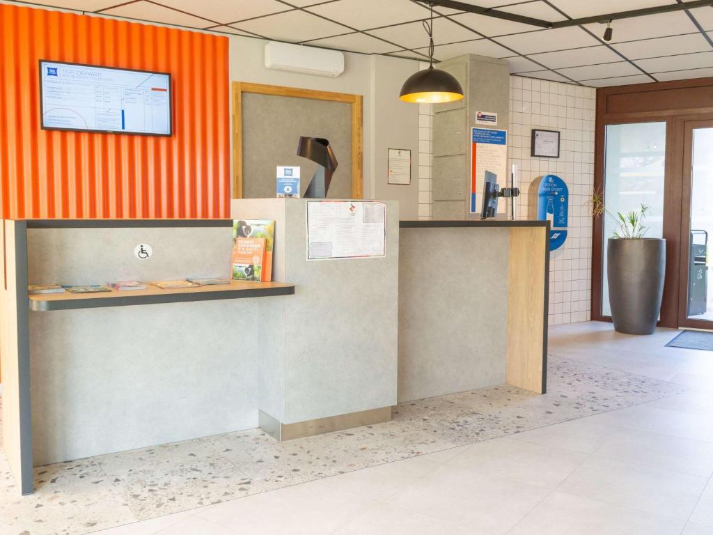 un mostrador en un restaurante con una pared naranja en ibis budget Tours Sud en Chambray-lès-Tours