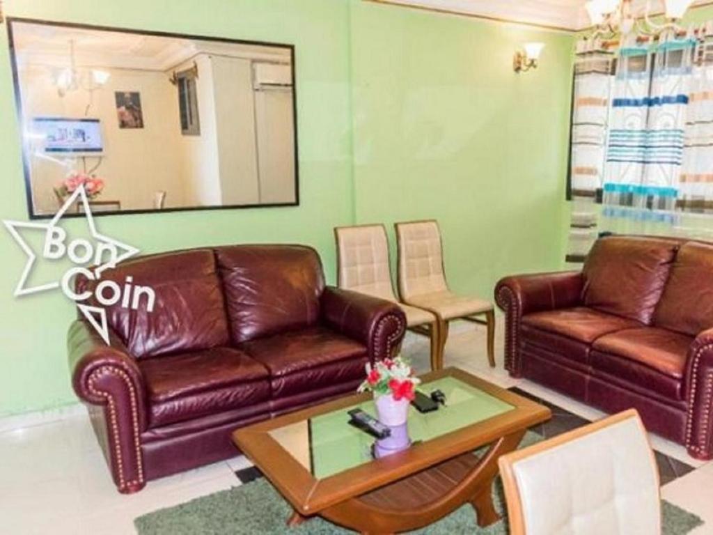 ein Wohnzimmer mit 2 Ledersofas und einem Tisch in der Unterkunft Appartement meublé à Douala, Bonamoussadi in Douala