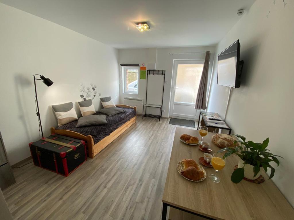 a living room with a bed and a table with food at Studio centre village Soligny la Trappe proche Mortagne au perche in Soligny-la-Trappe