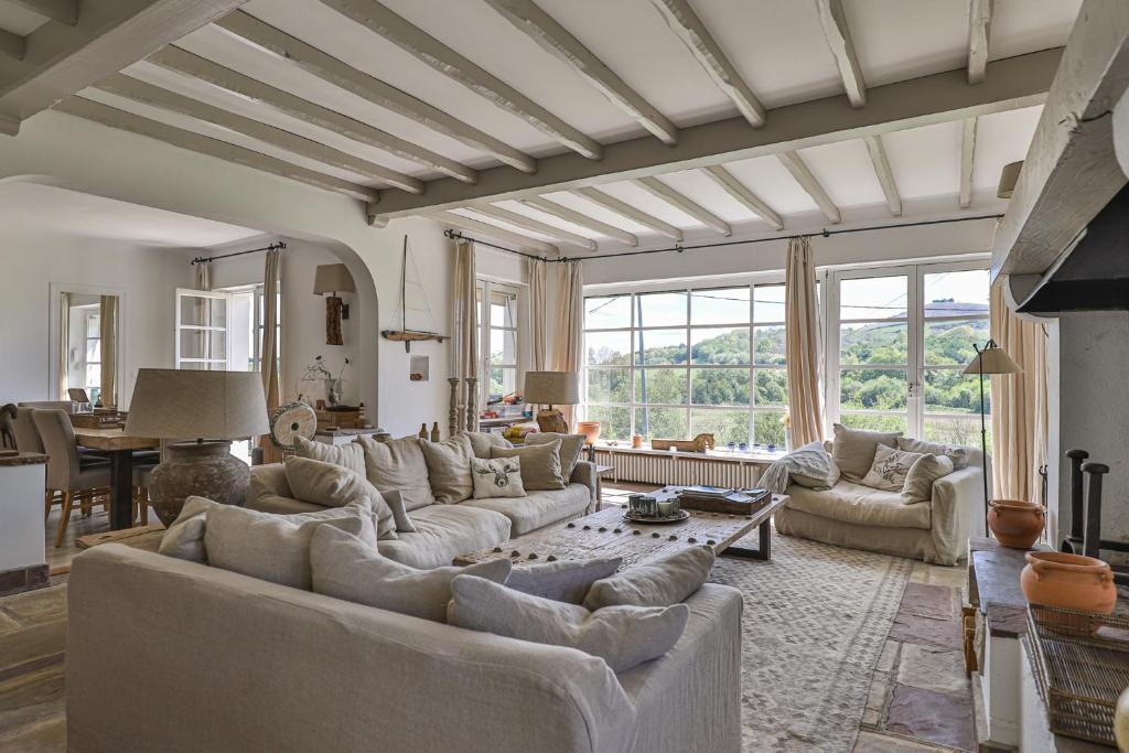 uma grande sala de estar com sofás e uma mesa em Belle maison basque avec grande Piscine chauffée (5x10m2) em Saint-Pée-sur-Nivelle