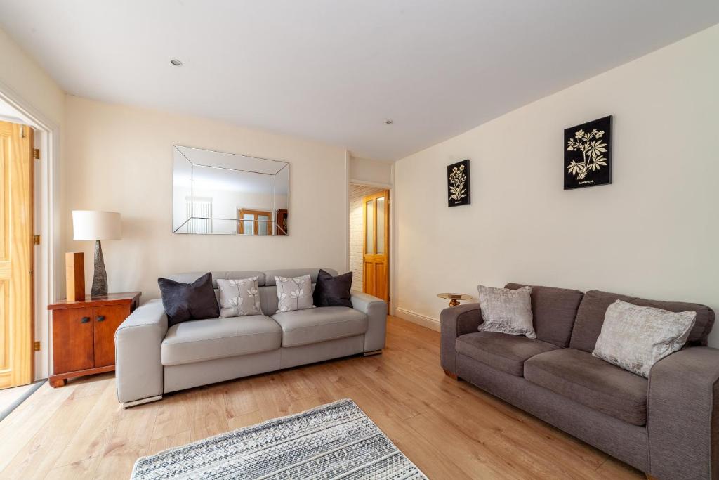 a living room with two couches and a mirror at Comfy 3BR grd floor flat wprivate garden, NE in London