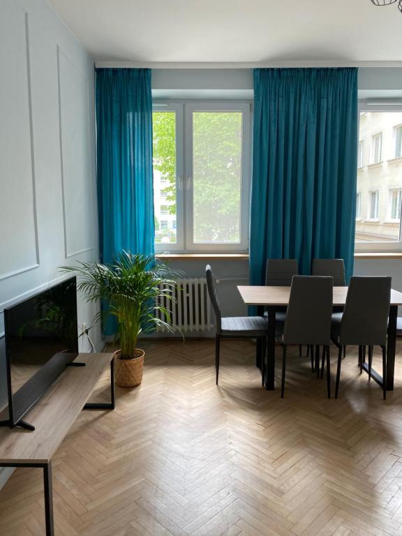 a living room with a table and chairs and blue curtains at Apartament III Aleja NMP in Częstochowa