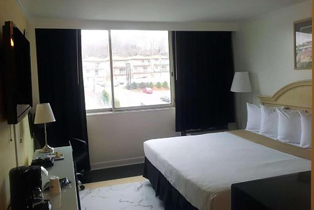 a hotel room with a bed and a window at Ramada by Wyndham North Bergen in North Bergen