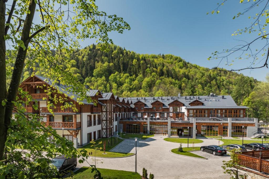 a large building with a mountain in the background at Szczawnica Park Resort & Spa in Szczawnica