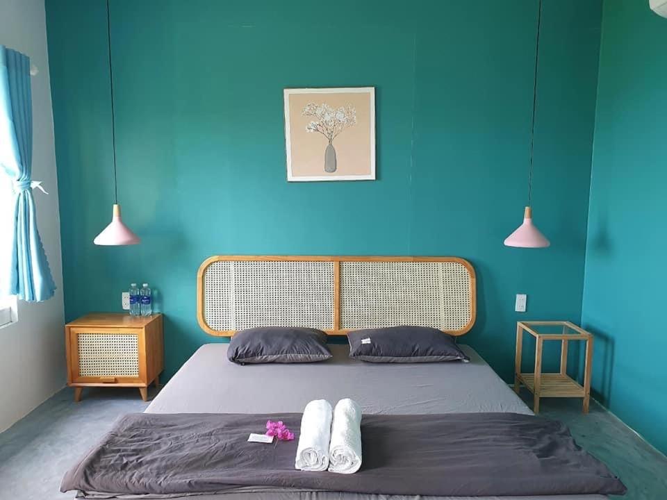 a bedroom with a bed with a blue wall at Kaktus home & kafe in Tuy Hoa