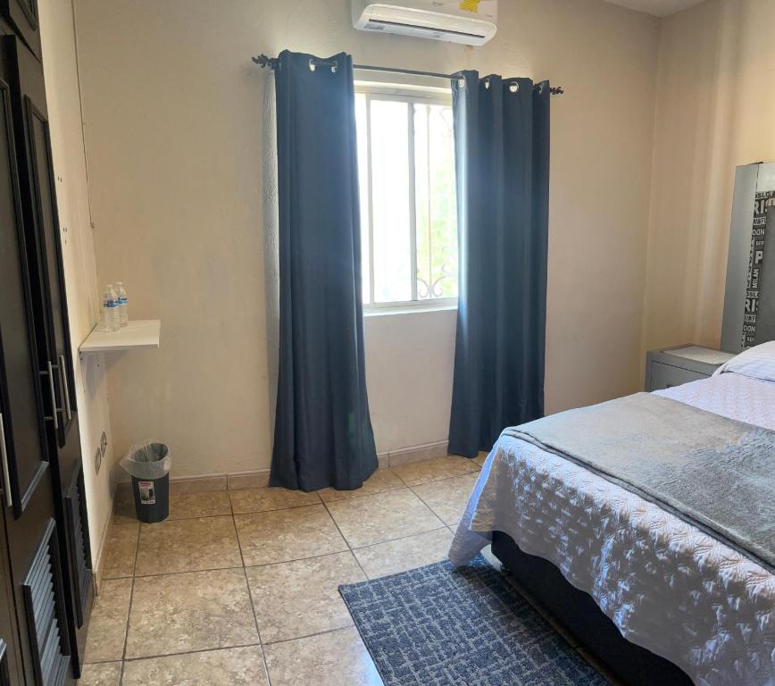 ein Schlafzimmer mit blauen Vorhängen und einem Fenster in der Unterkunft Recámara cedro in Saltillo