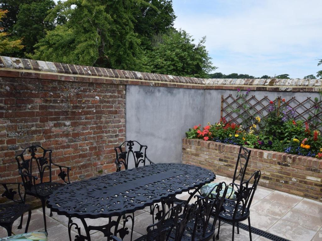 a table and chairs on a patio with a brick wall at 4 bed property in Hastings 85519 in Guestling