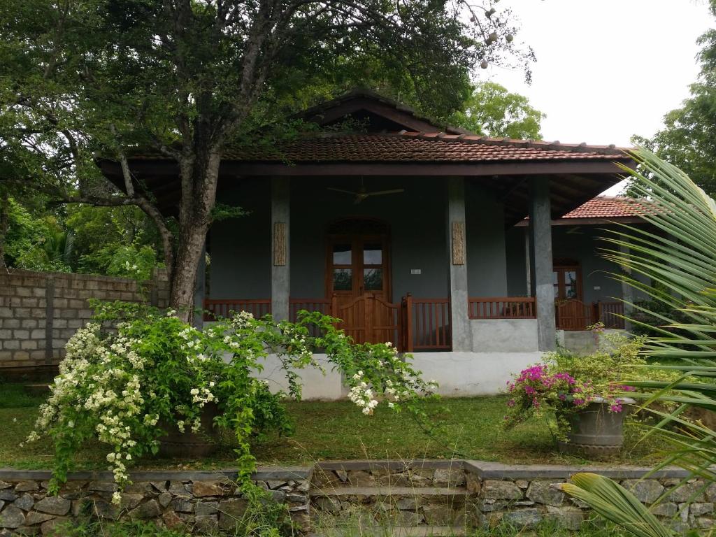 a small green house with flowers in front of it at Tranquality Chalets in Tangalle