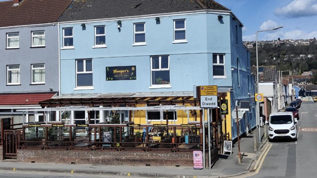ein blaues und gelbes Gebäude in einer Stadtstraße in der Unterkunft Hoopers Sandy Beach Guest Rooms in Swansea