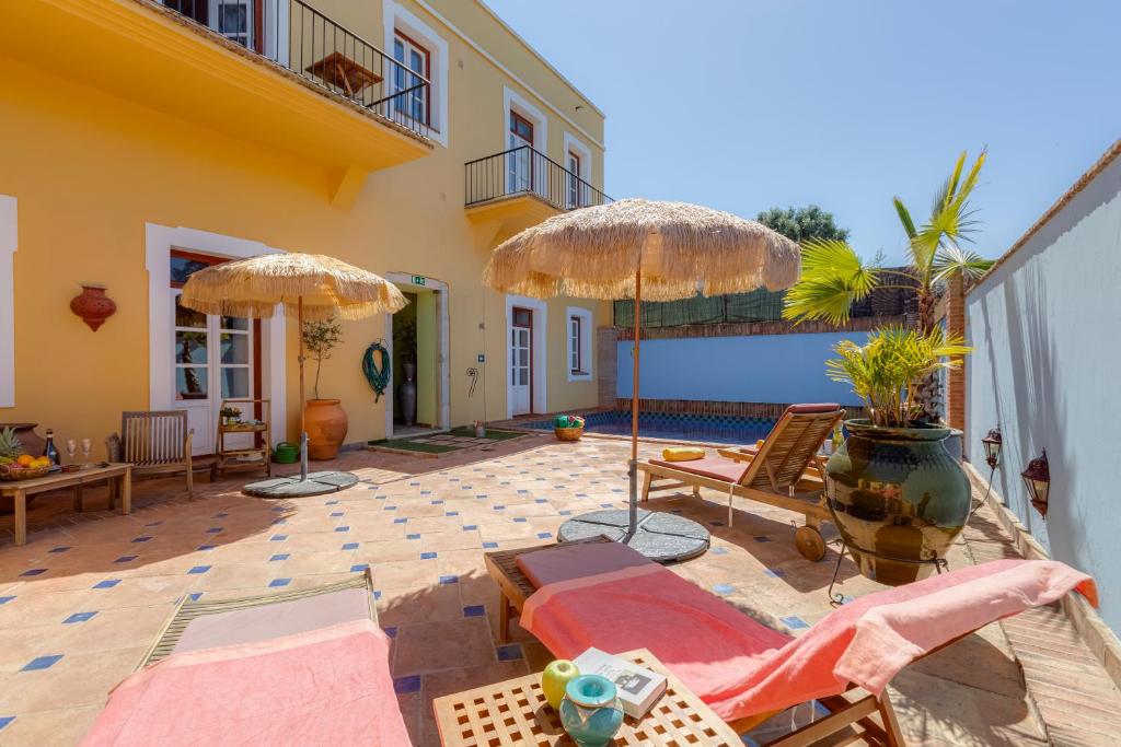 a patio with umbrellas and chairs and a pool at Casa da Moura in Lagos
