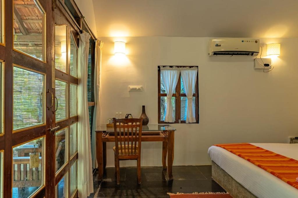 a bedroom with a desk and a bed and a window at The Bay Agonda in Agonda