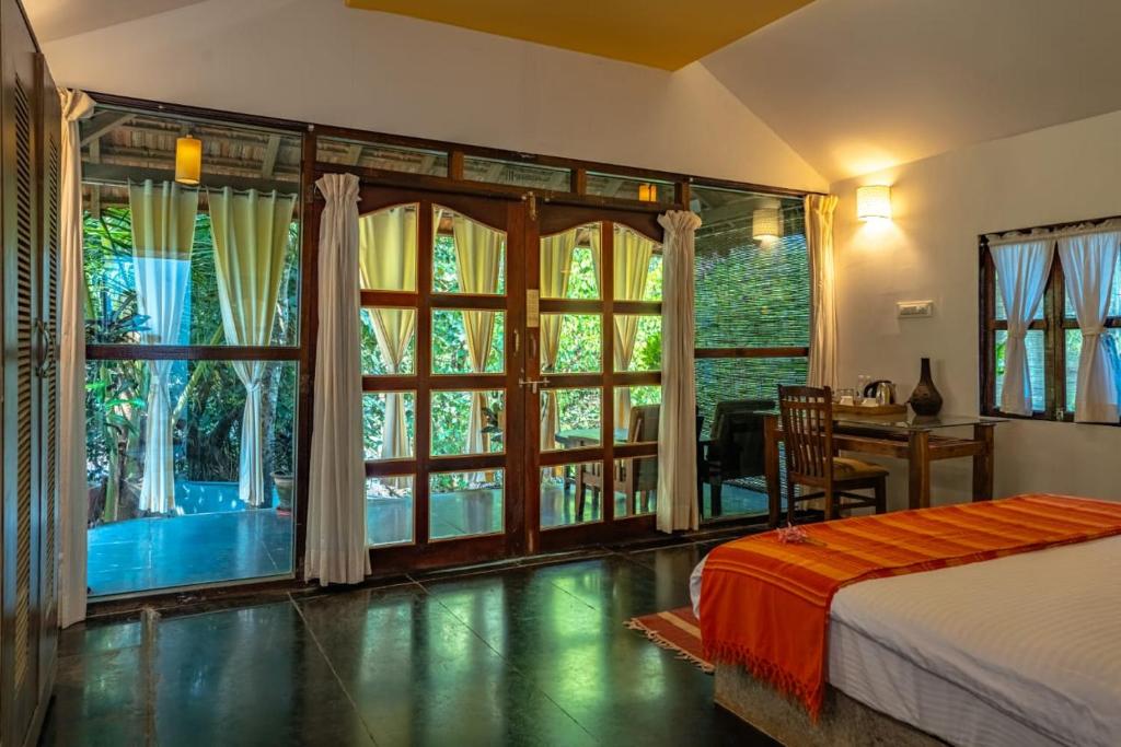 a bedroom with a bed and a large window at The Bay Agonda in Agonda