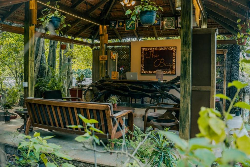 a wooden bench in a garden with a bar at The Bay Agonda in Agonda