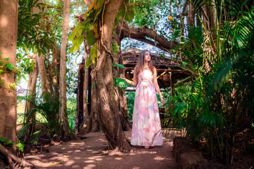 a woman in a dress standing next to a tree at The Bay Agonda in Agonda