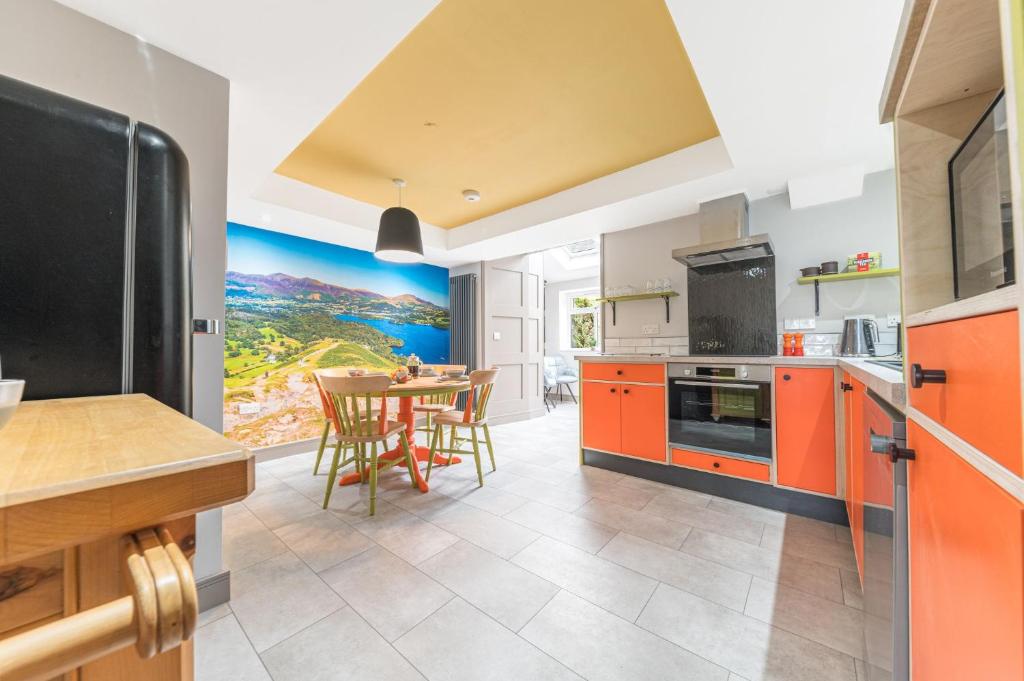 a kitchen with orange cabinets and a table with chairs at Blue Sky Cottage in Keswick